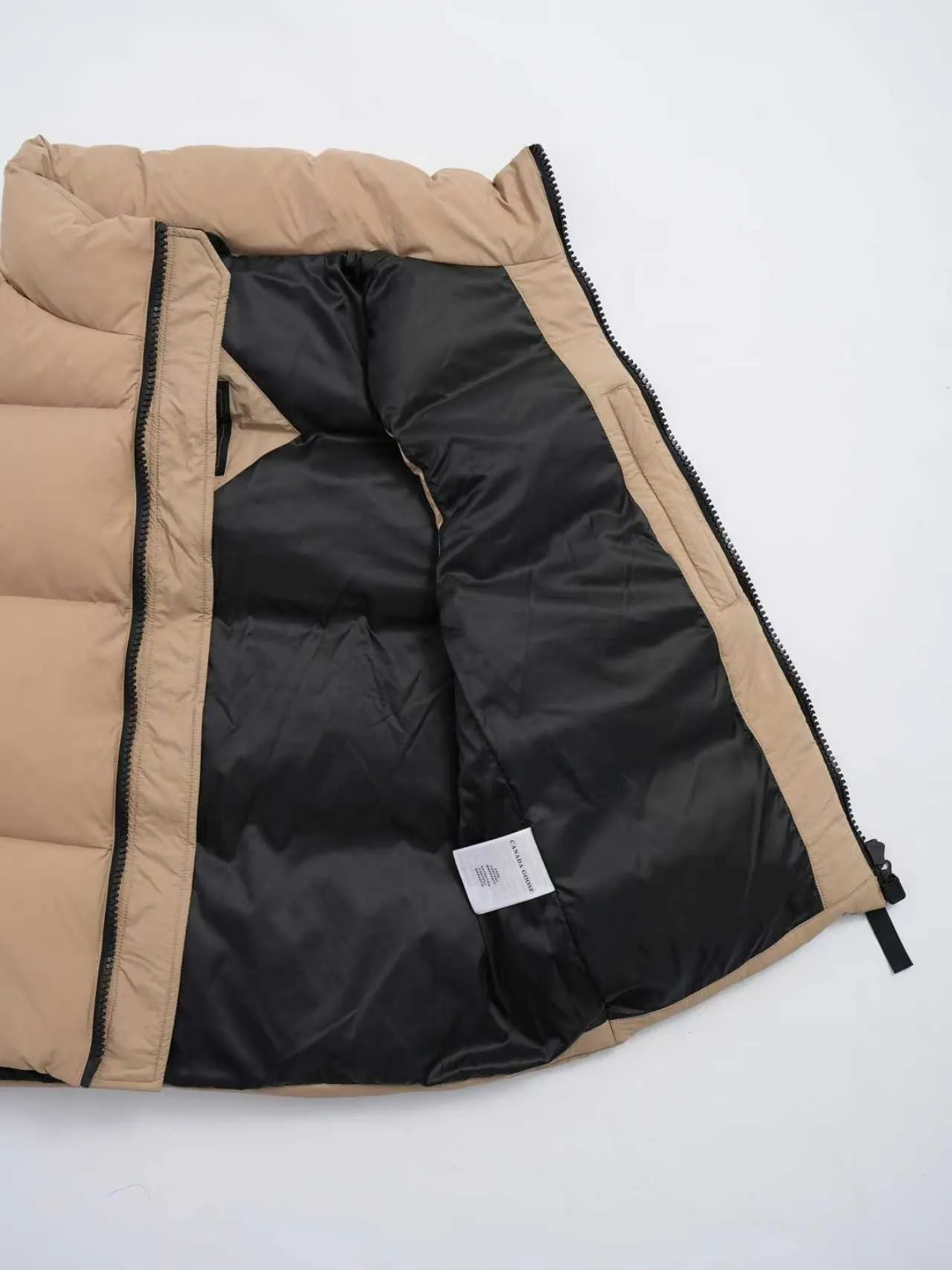 P580 Canada gooes Lawrence Down Vest (high version) With a durable shell and quilted body, the Lawrence Down Vest is a must-have for all seasons. The fabric has a durable soft touch. Longer hem at back for added protection. Reflective double-stripe grip tape at back. The Lawrence features an engineered down-filled collar to block strong winds, a two-way front zip and a longer rear hem. Color: black with red label, black with black label, desert color, ocean blue Size: XS -2XL